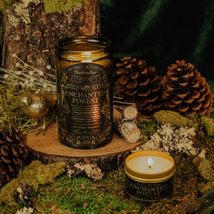 Enchanted Forest candle on a wooden stump with pine cones and moss in the background