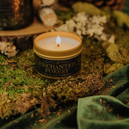 Candle in a 'Enchanted Forest' container on a natural setting with moss and foliage.