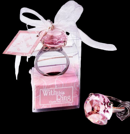 Pink gemstone ring in a decorative box with a bow on a white plate.