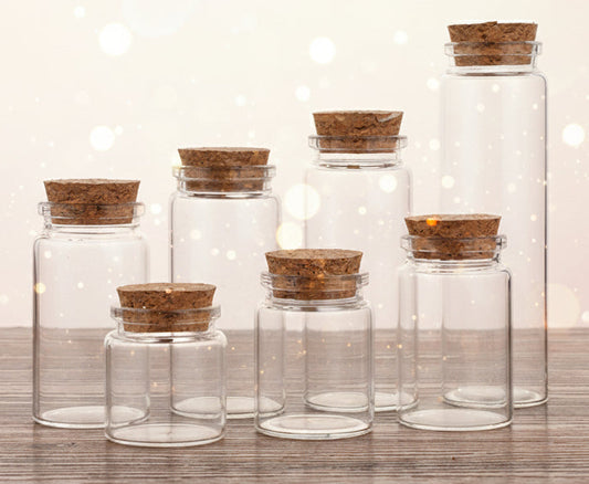 Set of clear glass jars with cork lids on a wooden surface
