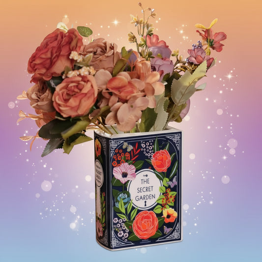 Floral arrangement in a decorative tin box with 'The Secret Garden' design on a wooden surface.