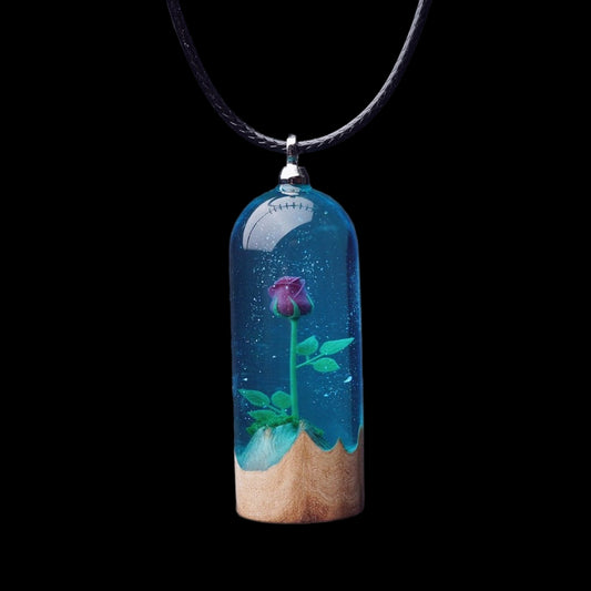 Necklace with a pendant featuring a rose in blue water and wooden base on a dark background