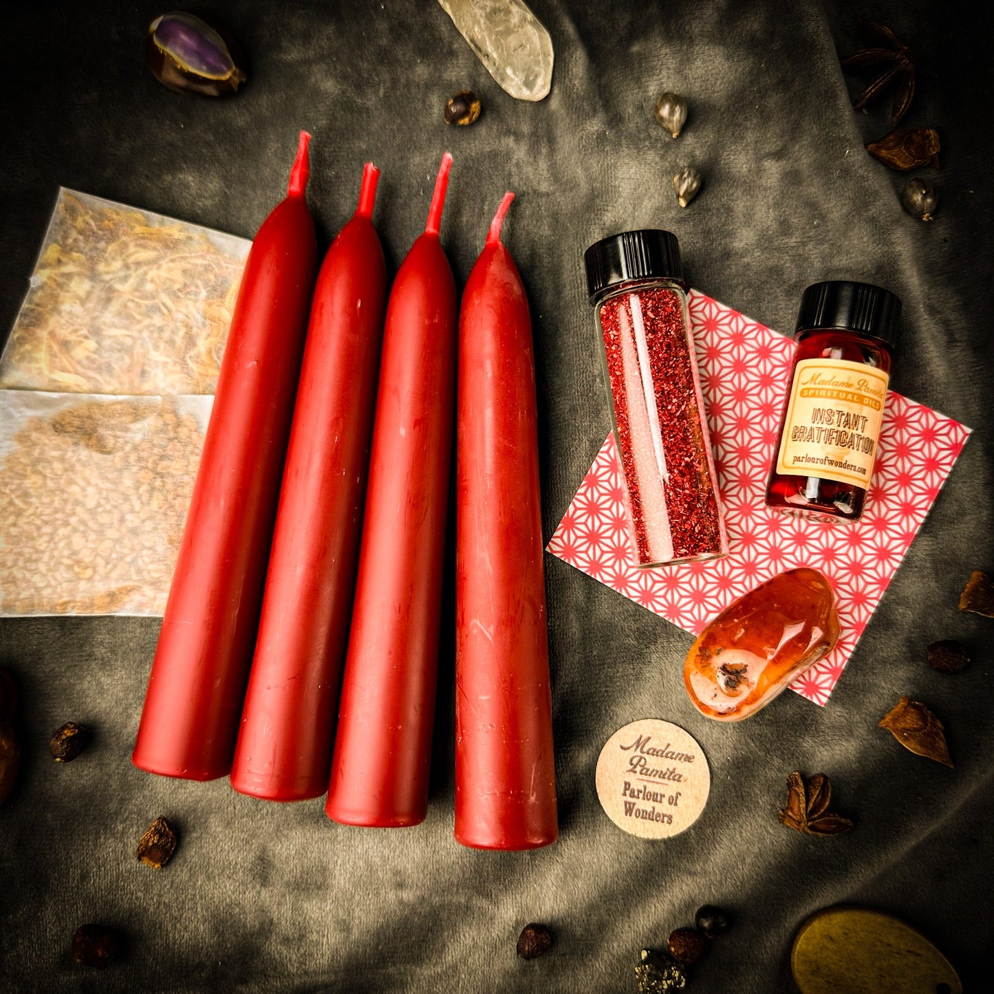 Red candles on a dark surface with small bottles and packaging