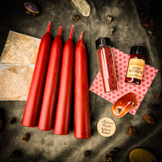 Red candles on a dark surface with small bottles and packaging