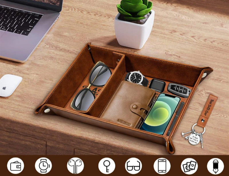 Brown leather tray on a desk with various items including sunglasses, wallet, phone, and keys.