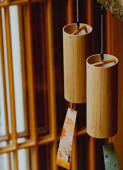 Two wooden wind chimes hanging against a blurred background with text about customization options.