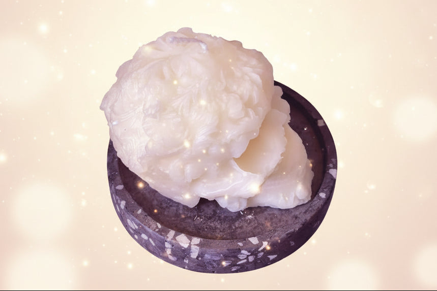 Two scoops of vanilla ice cream in a dark bowl on a textured blue background