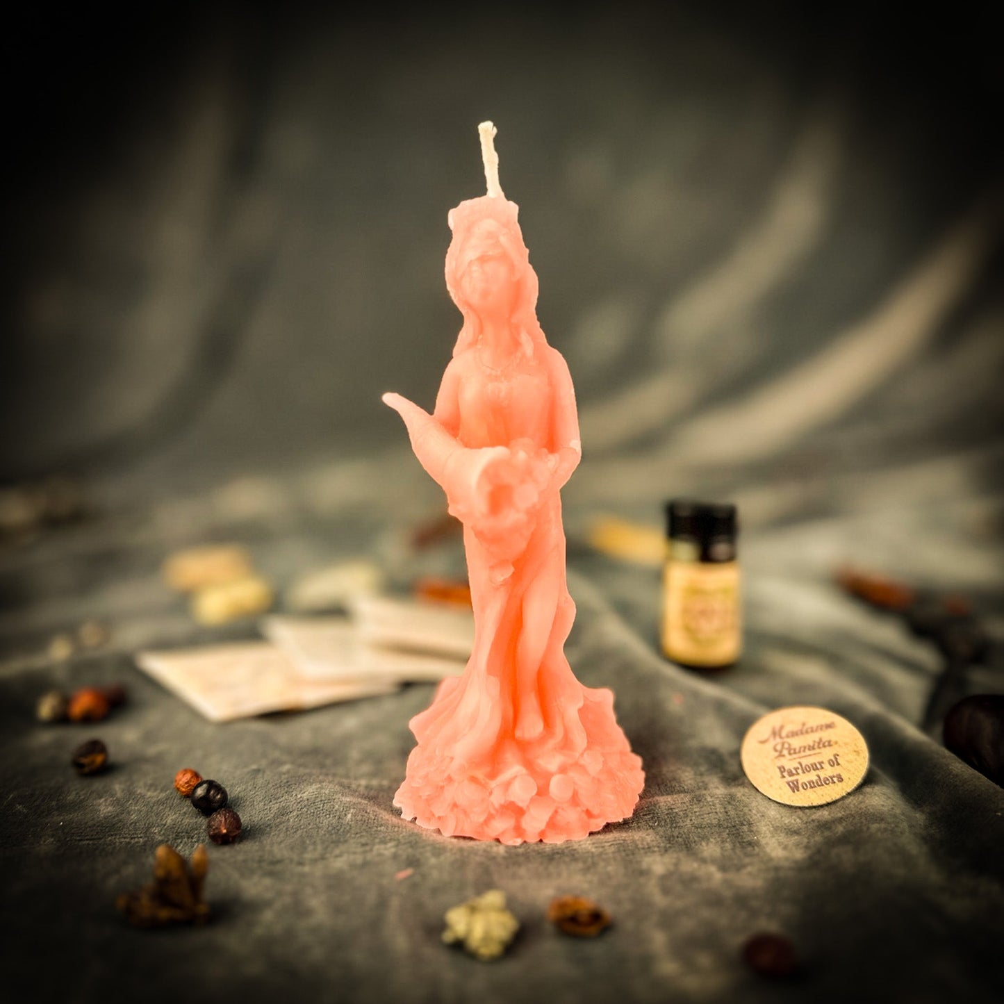 Pink statue candle on a dark surface with blurred background