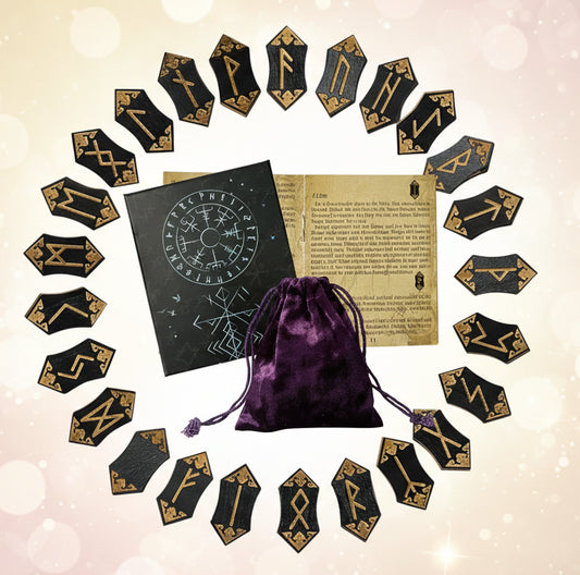 Set of black rune stones with gold symbols, a purple drawstring bag, and a book on a white background.