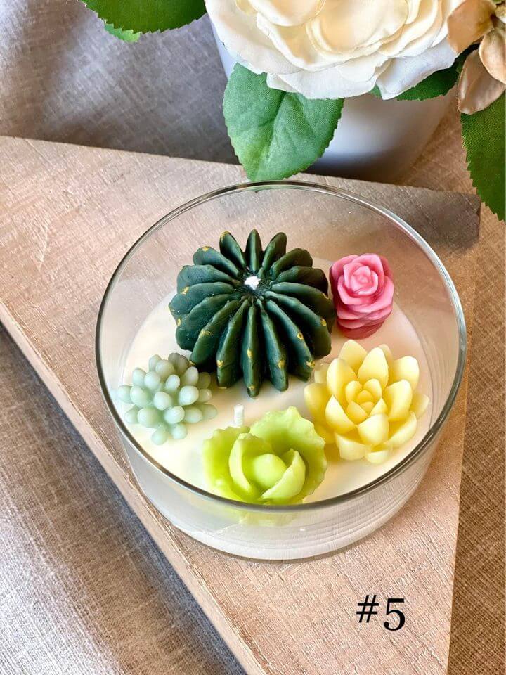 Glass bowl with colorful succulent-shaped candles on a wooden surface