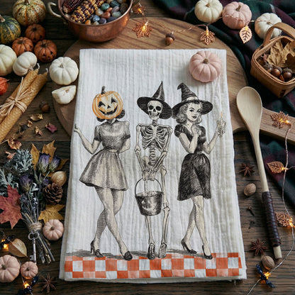 Halloween-themed towel with skeletons and pumpkins on a wooden surface with fall decorations.