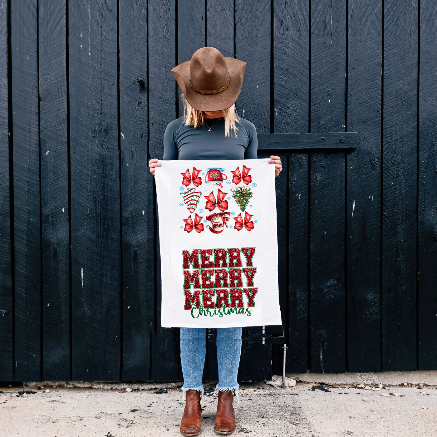 Person holding a 'Merry Christmas' towel against a dark wooden background