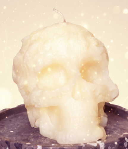 Skull-shaped candle on a black pedestal with a dark background