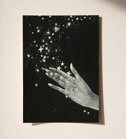 Greeting card with a hand holding stars against a black background on a beige surface