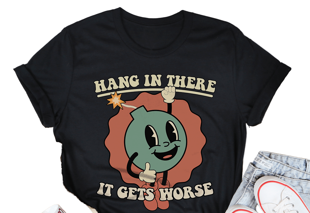 Black t-shirt with cartoon design and text 'Hang in there it gets worse' on a white surface with casual items.