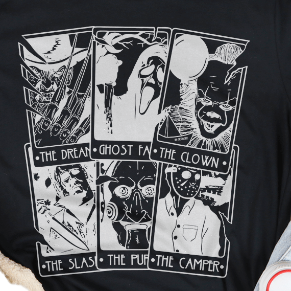Black t-shirt with graphic design on a white surface with casual items around