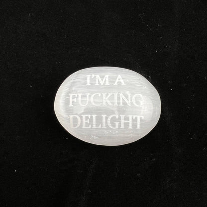 Clear stone with engraved text 'I'm a fucking delight' on a black background