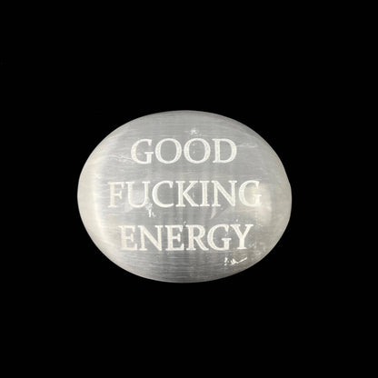 A round, semi-translucent white stone cabochon featuring the text 'GOOD FUCKING ENERGY' in a distressed white font, set against a solid black background.