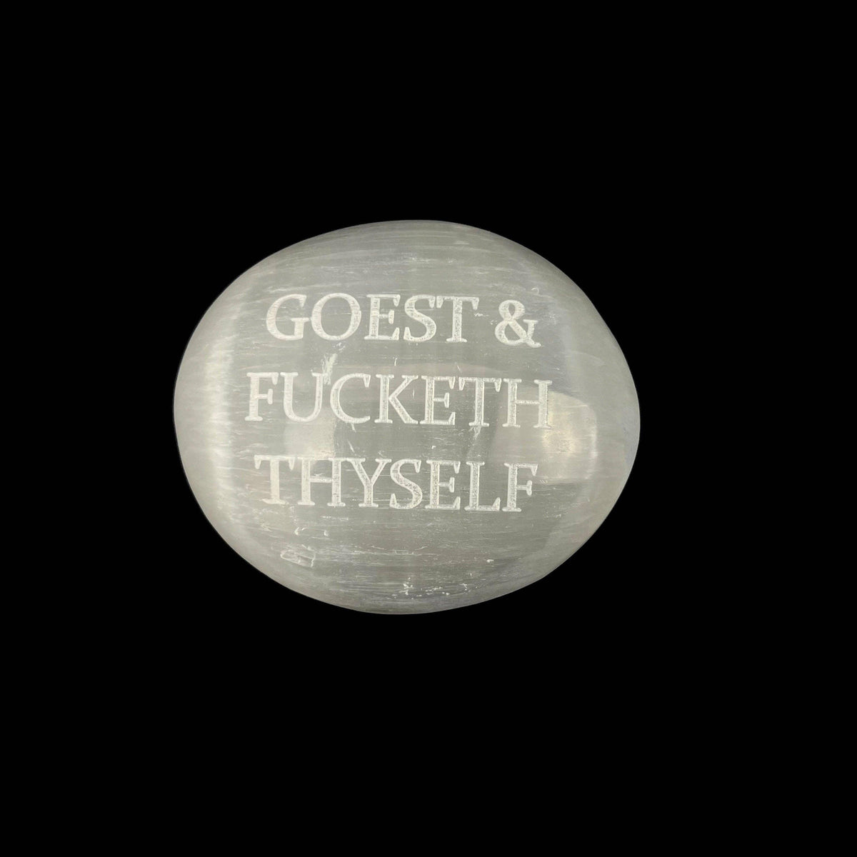 Round stone with engraved text on a black background