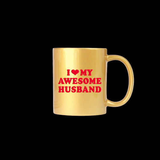 Gold mug with red text 'I ❤️ MY AWESOME HUSBAND' on a white surface with a plant in the background