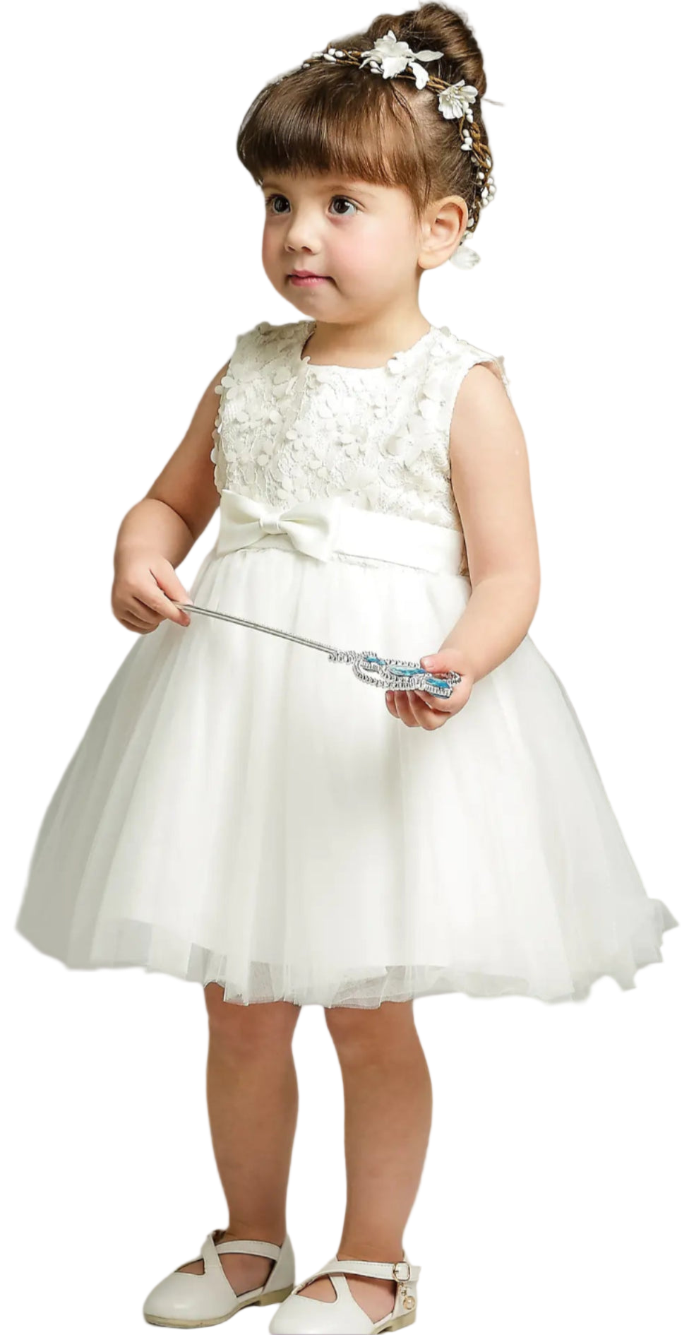 Young girl in a white dress holding a toy on a plain background