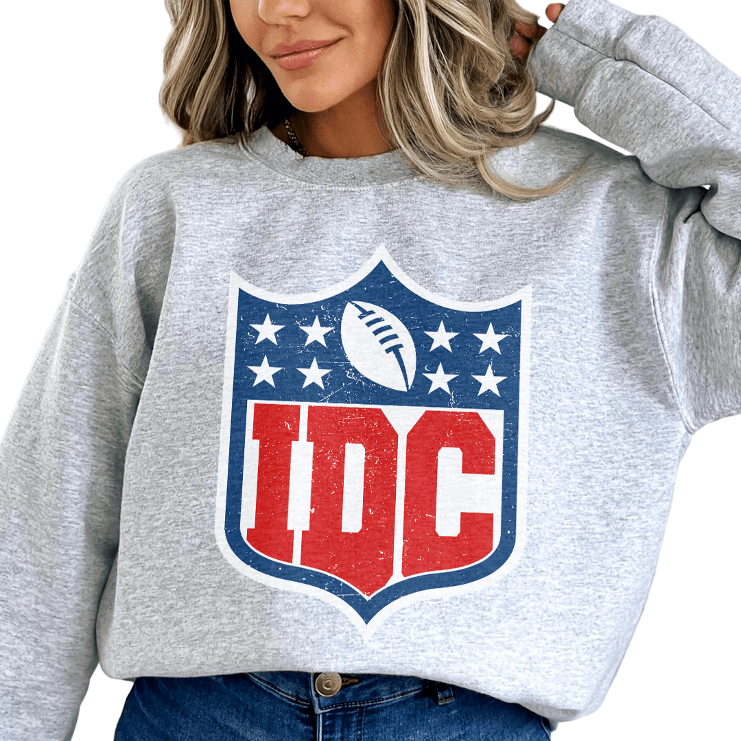 Person wearing a gray sweatshirt with a logo featuring 'IDC' letters on a white background
