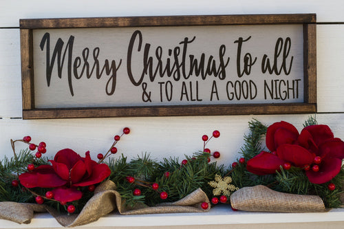 Decorative Christmas sign with 'Merry Christmas to all & to all a good night' text, surrounded by red flowers and greenery.