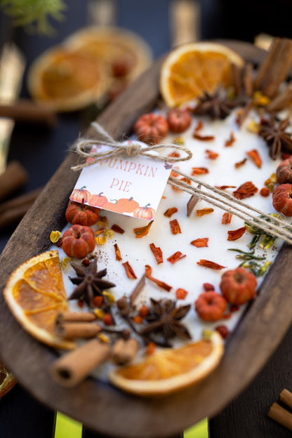 Decorative display of pumpkin pie with spices and oranges on a wooden board.