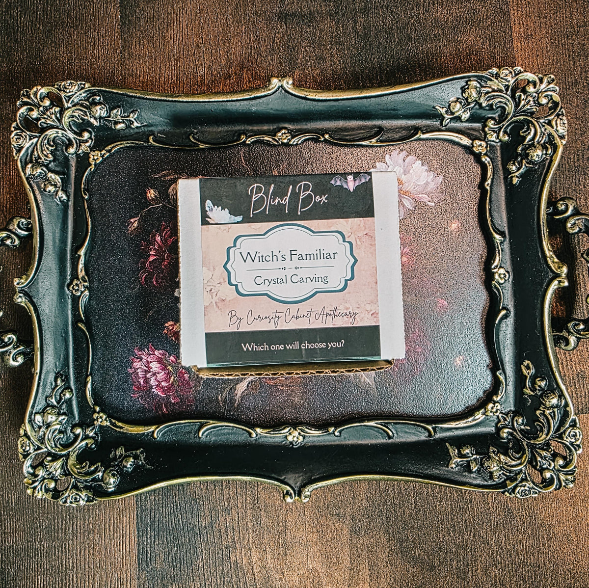 Decorative frame with a card labeled 'Witch's Familiar Crystal Carving' on a wooden surface