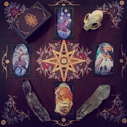 A styled flat-lay of a tarot card deck and four illustrated cards arranged around a central pentagram on a dark patterned cloth, with crystals and a small animal skull as props.