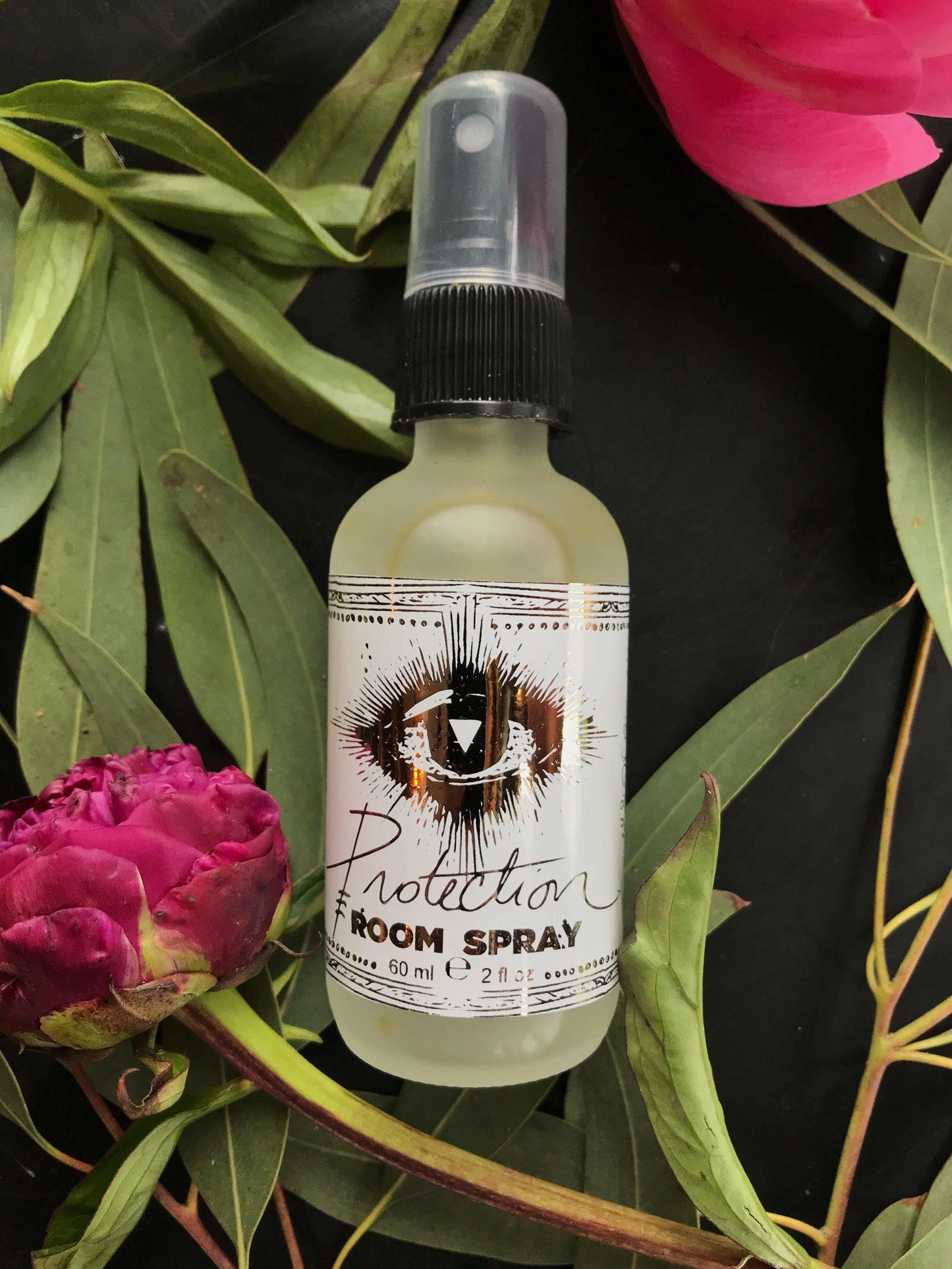 Room spray bottle labeled 'Protection' with flowers and leaves in the background