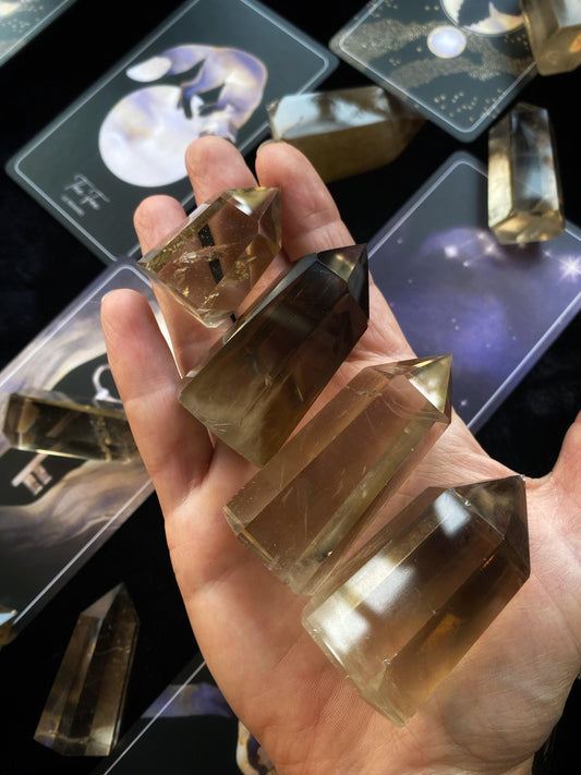Hand holding crystal-like objects with tarot cards in the background