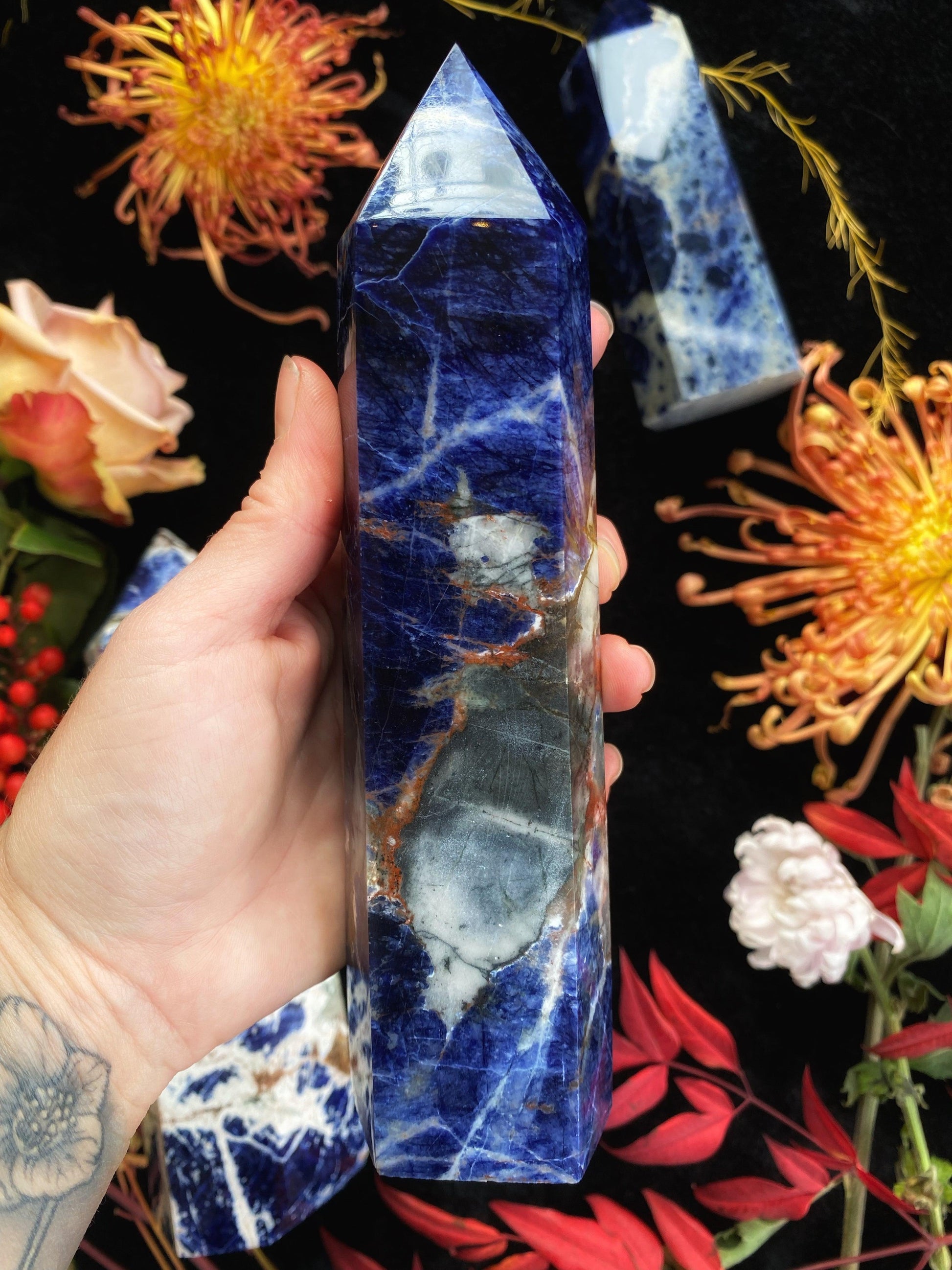 Hand holding a blue marbled crystal with flowers in the background
