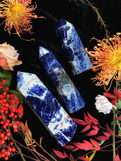 Blue marbled crystal sticks on a black surface with colorful flowers