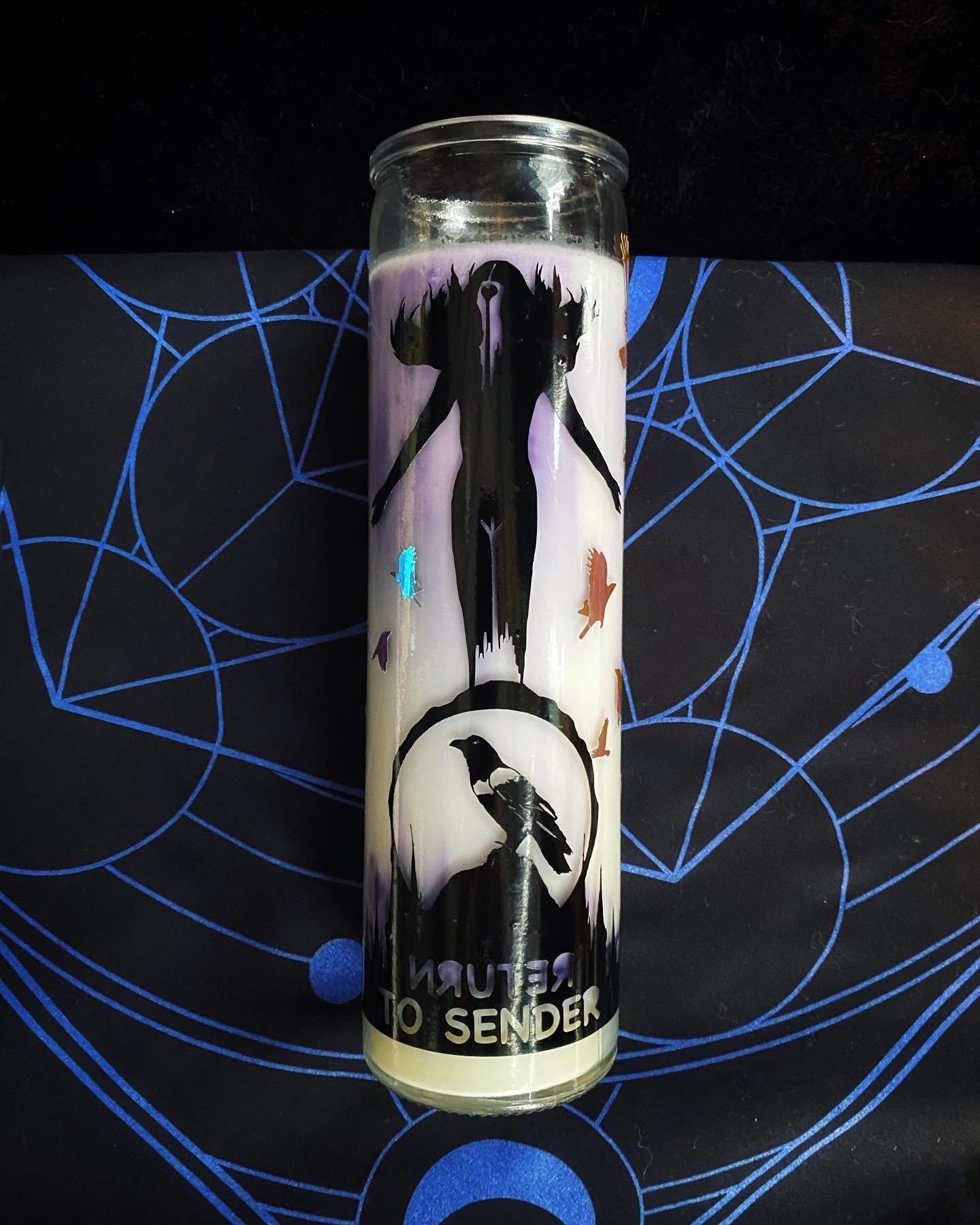 Candle with artistic design on a black background with blue geometric patterns