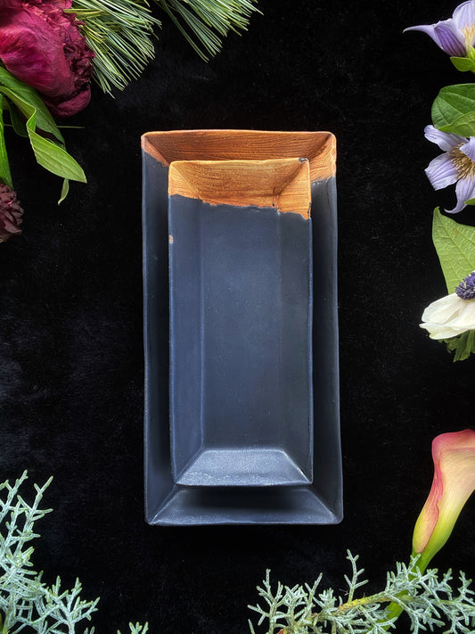 Rectangular blue dish with wooden rim on a black background with floral and greenery elements.