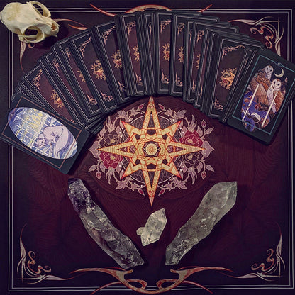 A tarot card deck arranged in a fan and stacked on a dark decorative mat with a central pentagram design, alongside a skull, crystals, and illustrated cards showing skeletal figures.