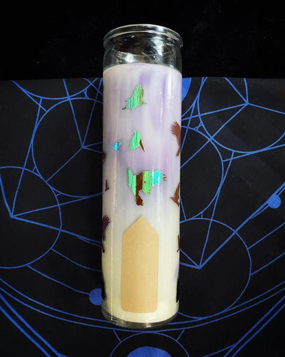 Decorative candle with a house design on a black surface with blue patterns