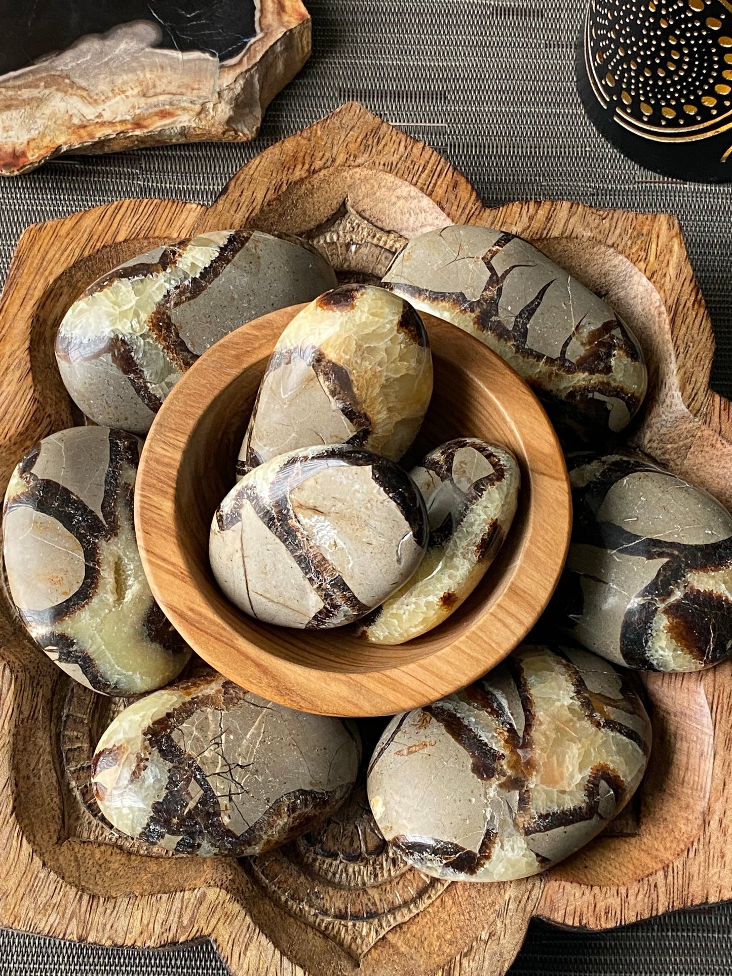 Decorative stone pieces with a wooden bowl on a textured surface