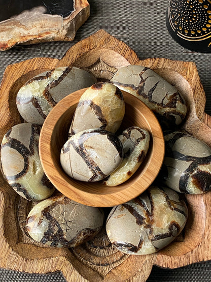 Decorative stone pieces with a wooden bowl on a textured surface