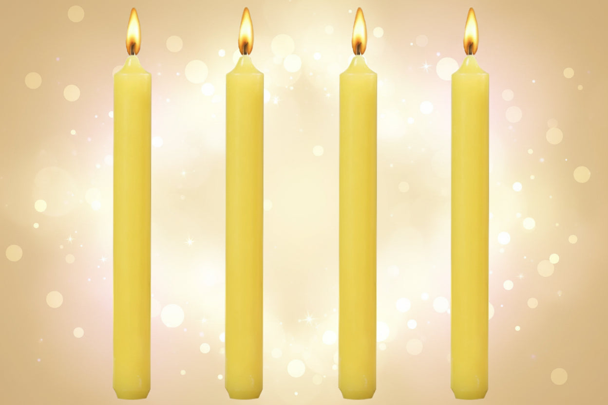 Four yellow candles with lit wicks on a white background