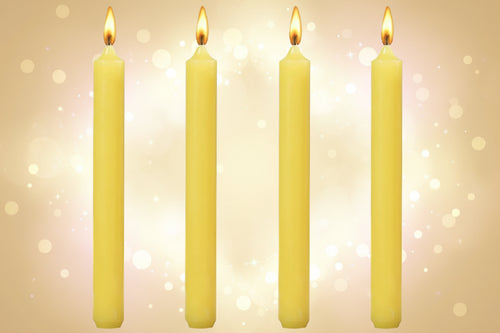 Four yellow candles with lit wicks on a white background