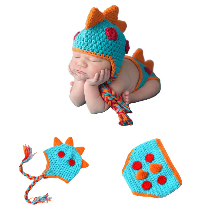 Newborn baby wearing a colorful dinosaur-themed crochet outfit on a blue blanket.