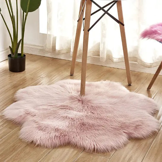Pink fluffy rug on a wooden floor with a plant and chair in the background