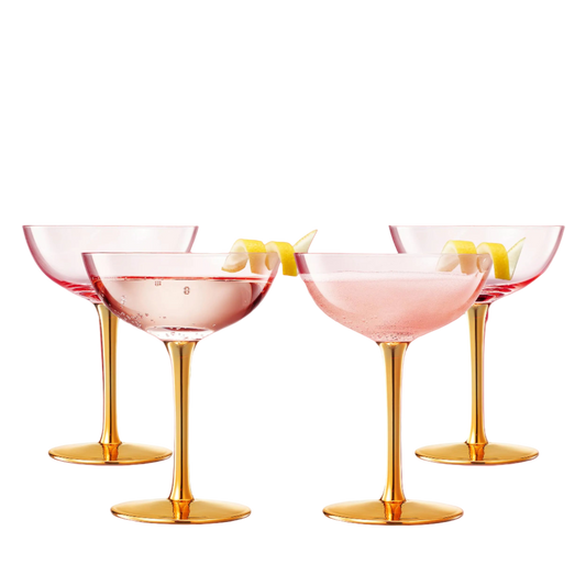 Set of four cocktail glasses with gold stems and pink interiors, accompanied by a decorative box.