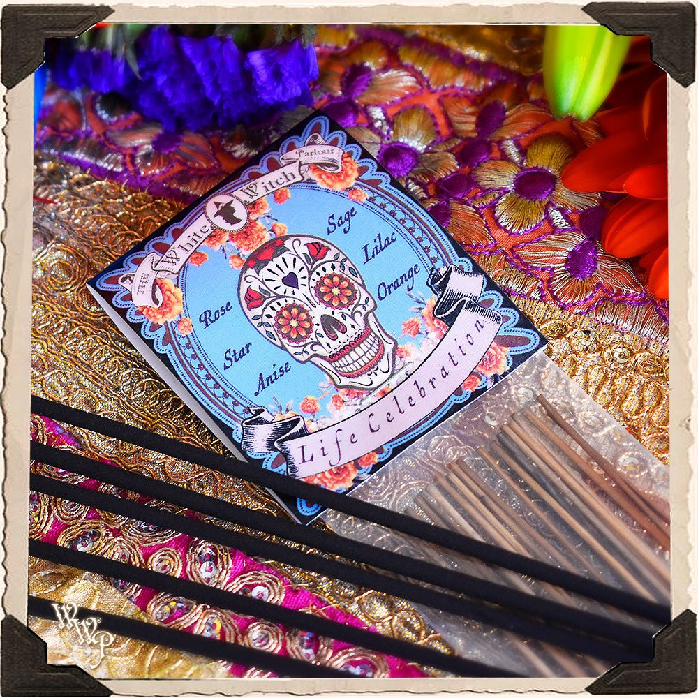 Decorative card with a skull design on a colorful, textured background with incense sticks.