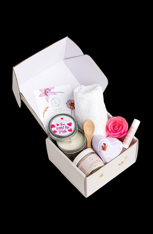 Gift set with candles, flowers, and other items in a box on a white background