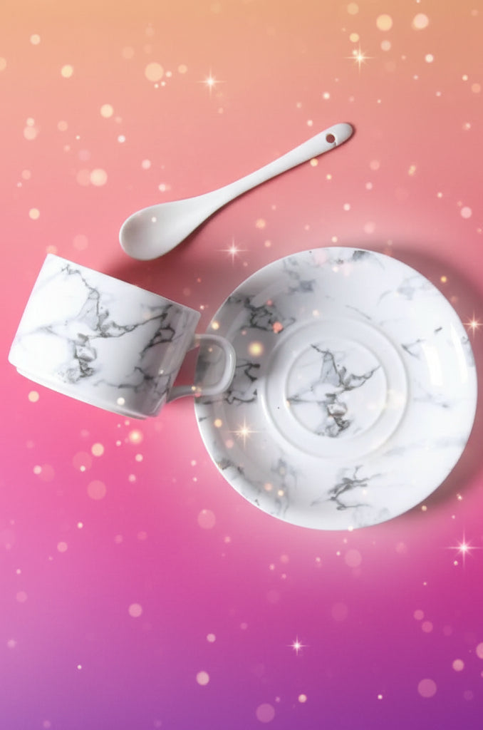 Marble-patterned ceramic cup, saucer, and spoon on a gray surface