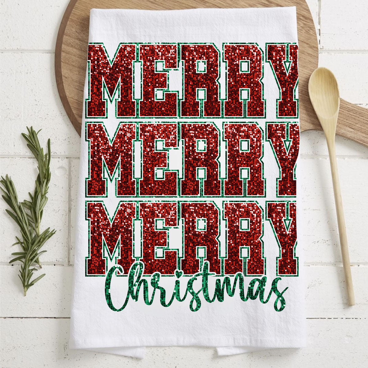 White towel with red and green 'Merry Christmas' text on a wooden surface.