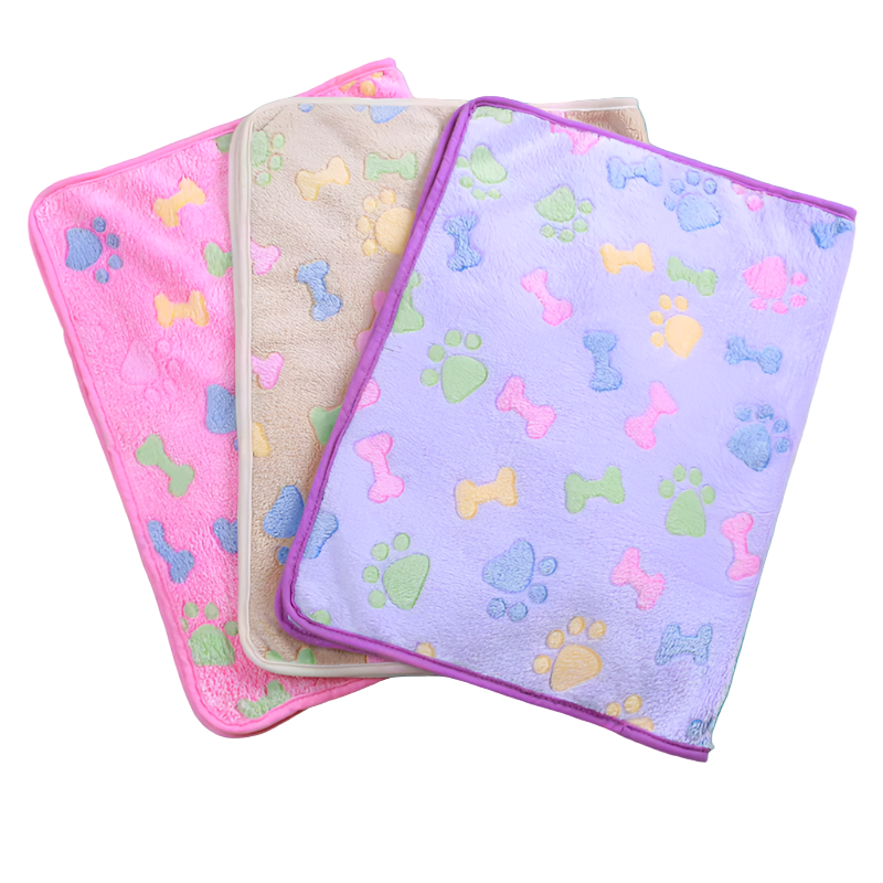 Three pet towels with colorful paw and bone patterns on a beige carpet.